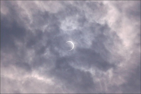 ちょうど厚めの雲に入った三日月型の太陽